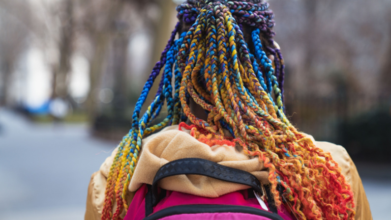 Young woman bright vivid colorful afro braids dreadlocks hairstyle. Teenager funky beauty fashion style.