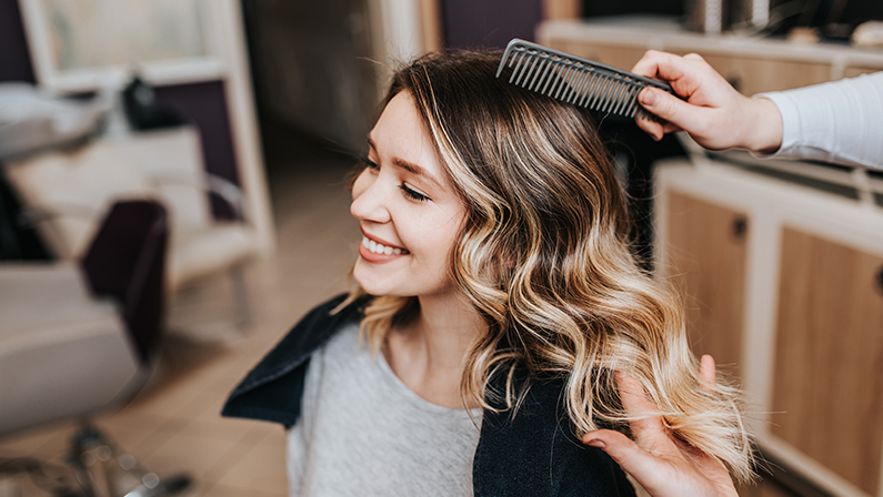 Beautiful hairstyle of young woman after dyeing hair and making highlights in hair salon.