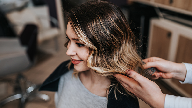 Beautiful hairstyle of young woman after dyeing hair and making highlights in hair salon.